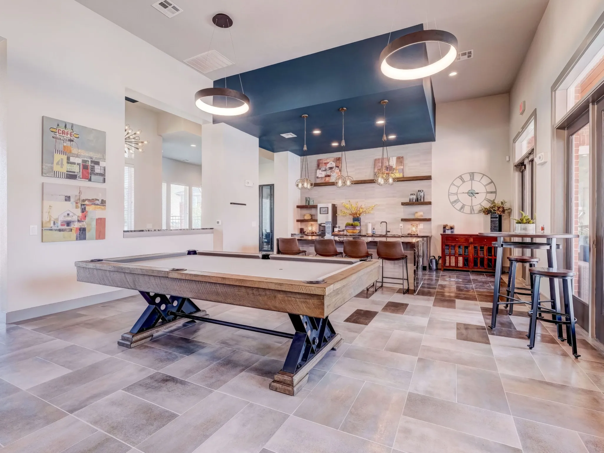 "Spacious game room and entertainment space at The Emerson at Forney with a pool table, modern bar seating, and unique lighting."