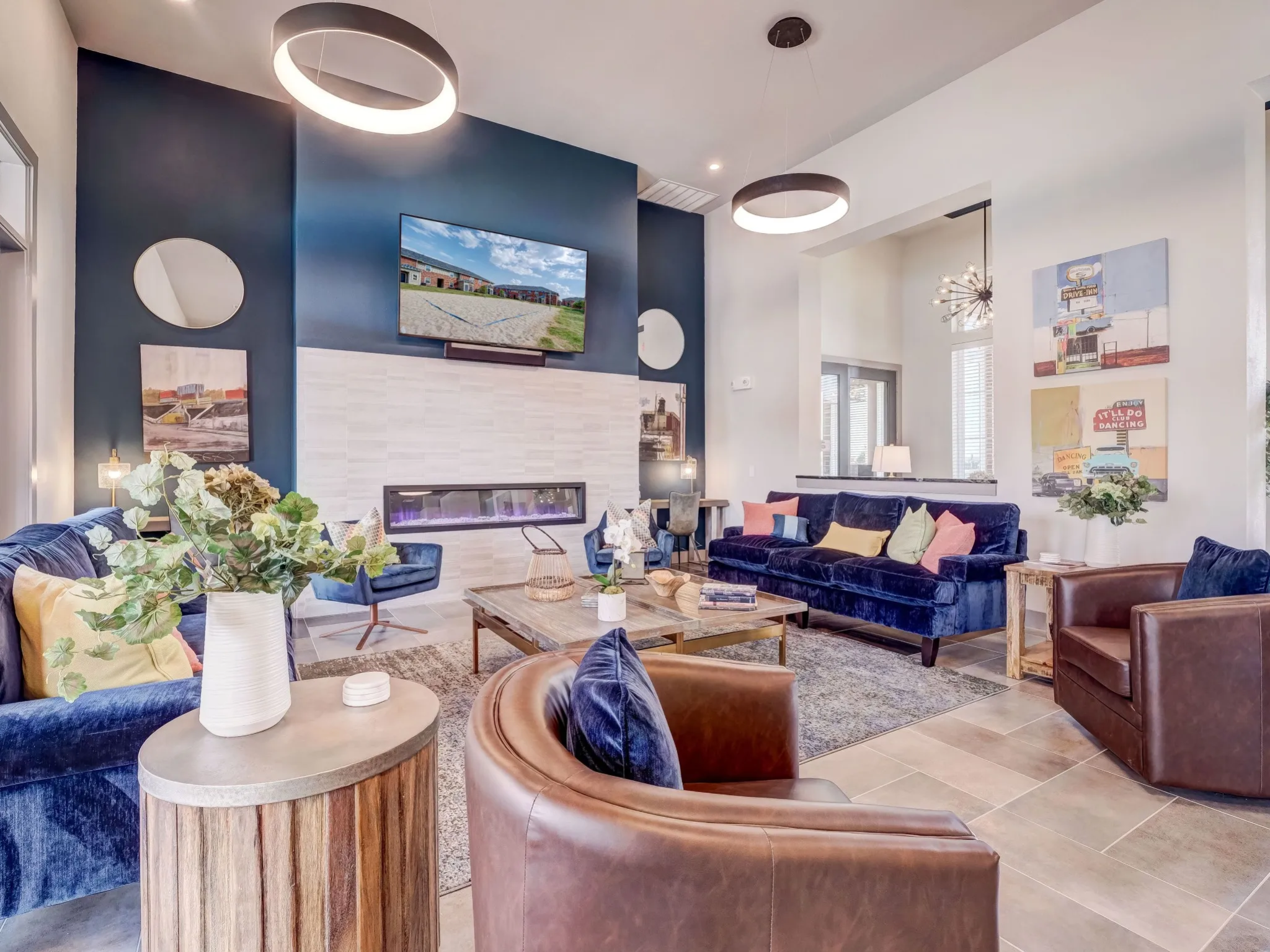 "Stylish resident lounge at The Emerson at Forney Luxury Apartments featuring modern seating, a fireplace, and vibrant decor."