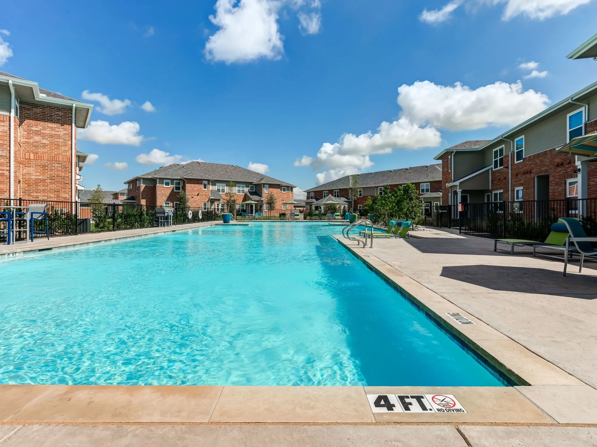 "Resort-style pool with crystal-clear water surrounded by comfortable lounge chairs at The Emerson at Forney Apartments."