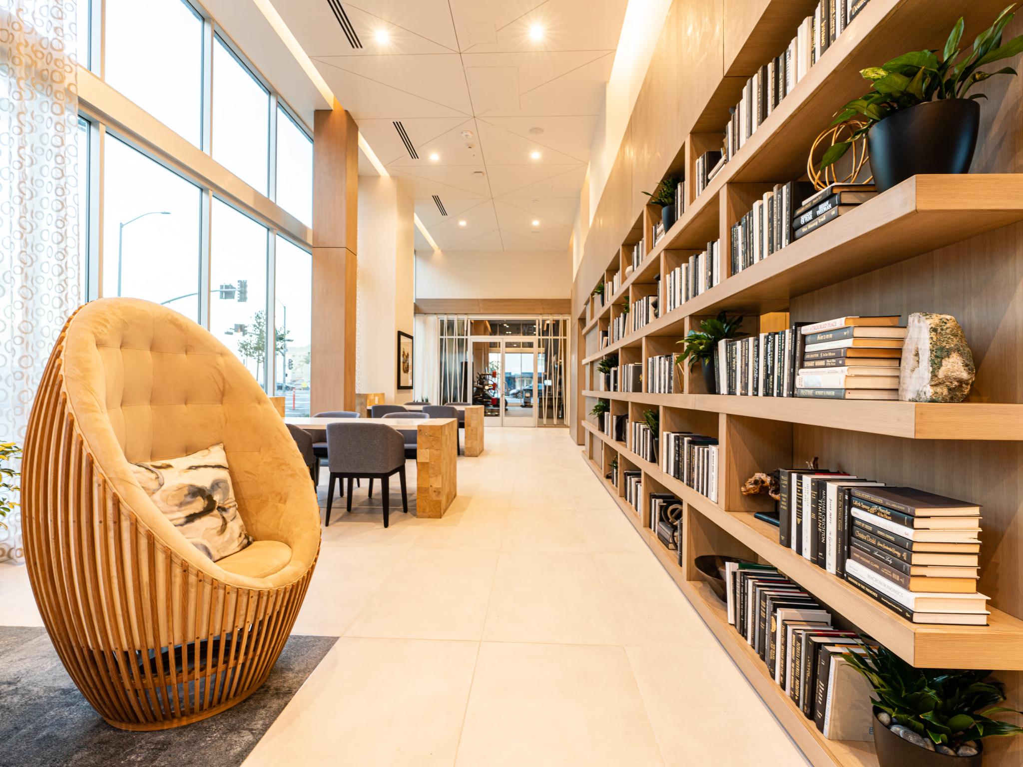 Inviting library and co-working space at The Linden Luxury Apartments with floor-to-ceiling bookshelves, cozy seating, and abundant natural light.