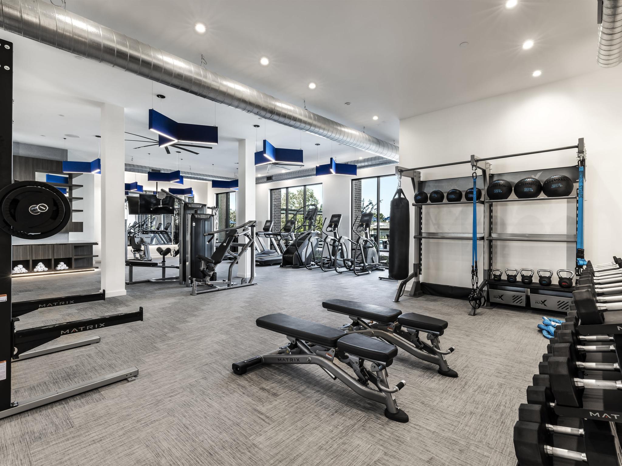 The Warner Apartments' state-of-the-art fitness center, complete with cardio machines, free weights, and strength training equipment in a bright and spacious setting.