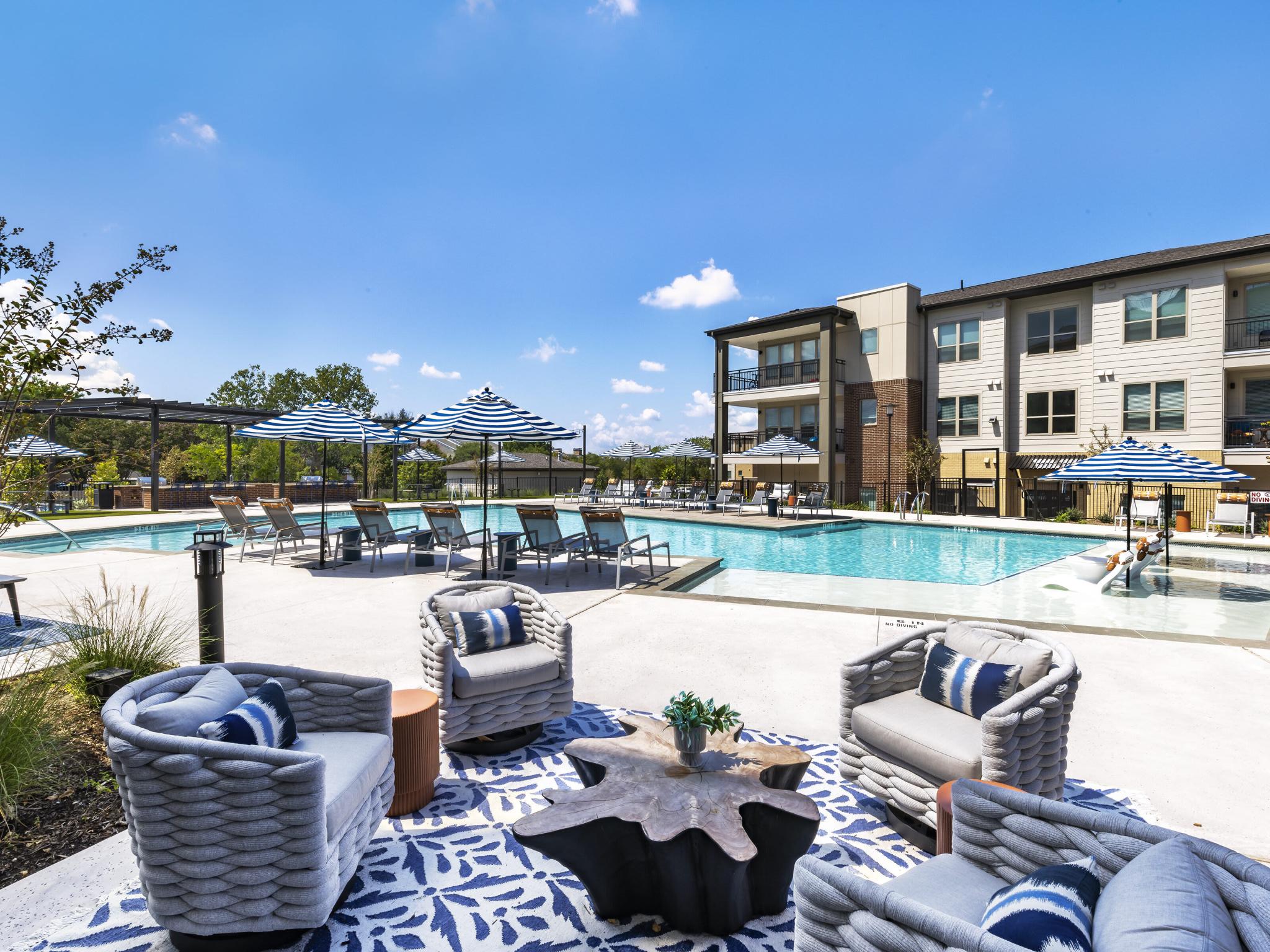 The Warner Apartments' resort-style pool area, offering stylish lounge seating, shaded cabanas, and an inviting atmosphere for relaxation and socializing.