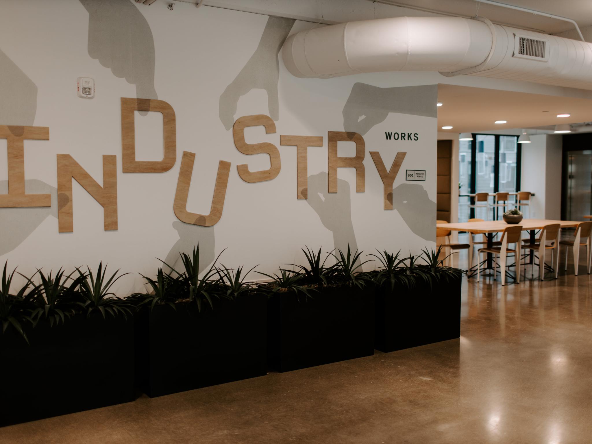 A stylish coworking space in Industry Columbus Apartments with a bold "Industry Works" wall design, contemporary seating, and an open-concept layout for productivity and collaboration.