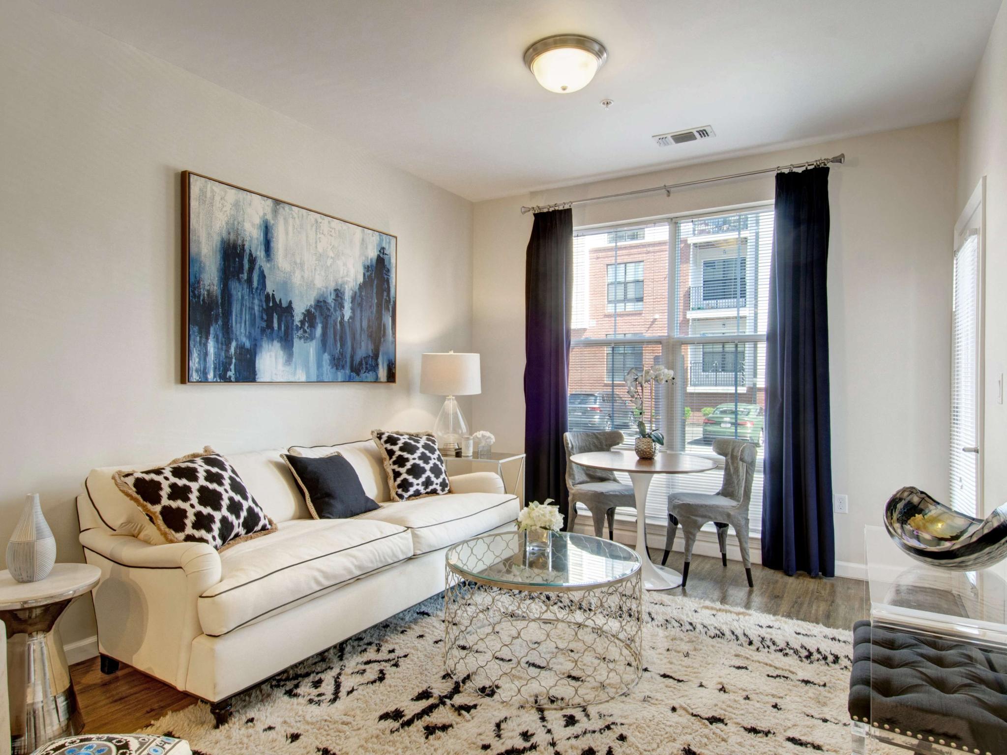 Bright living room with white sofa, abstract art, and large window bringing in natural light.