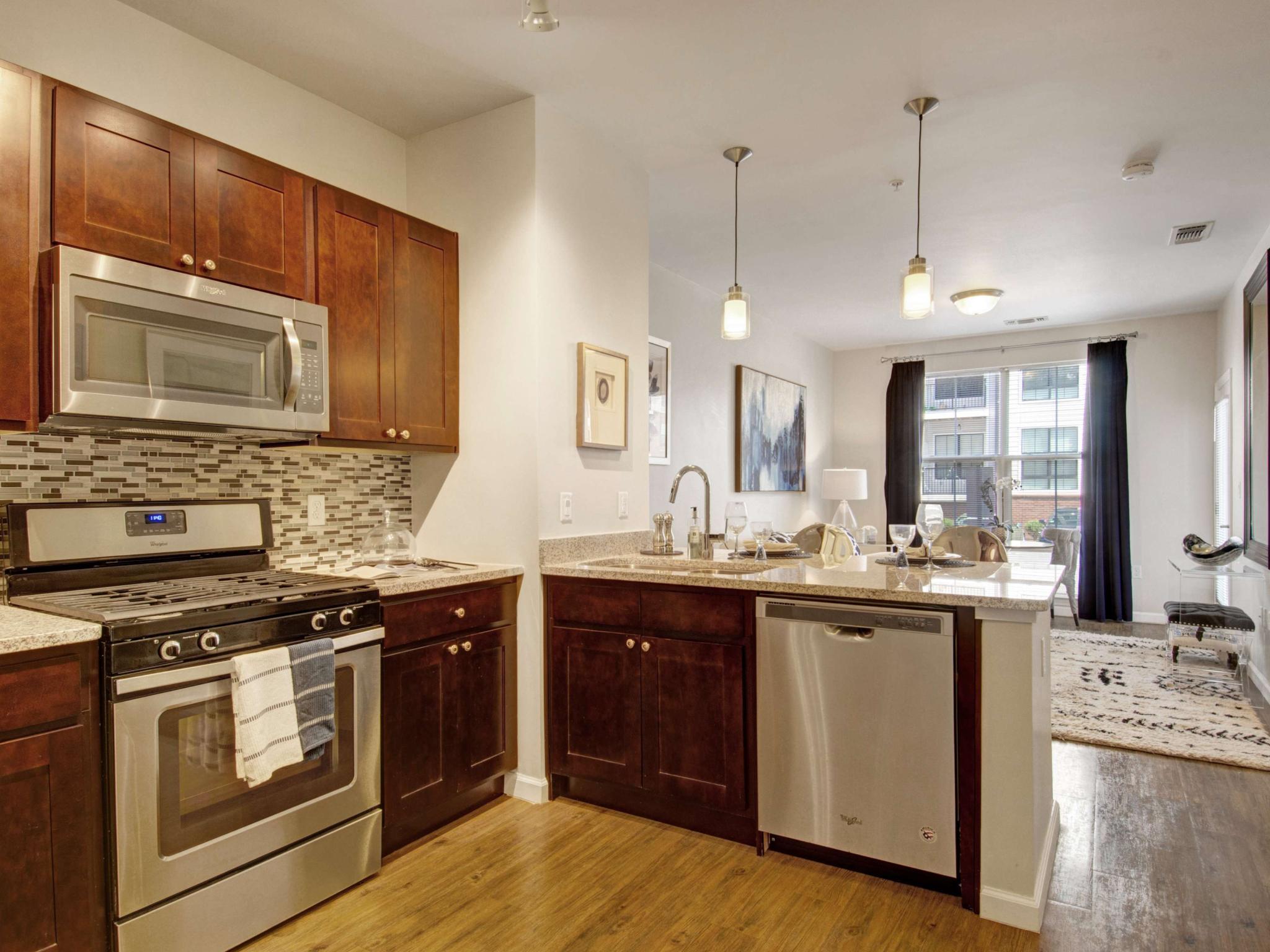Contemporary kitchen with dark wood cabinets, stainless steel appliances, and mosaic tile backsplash.