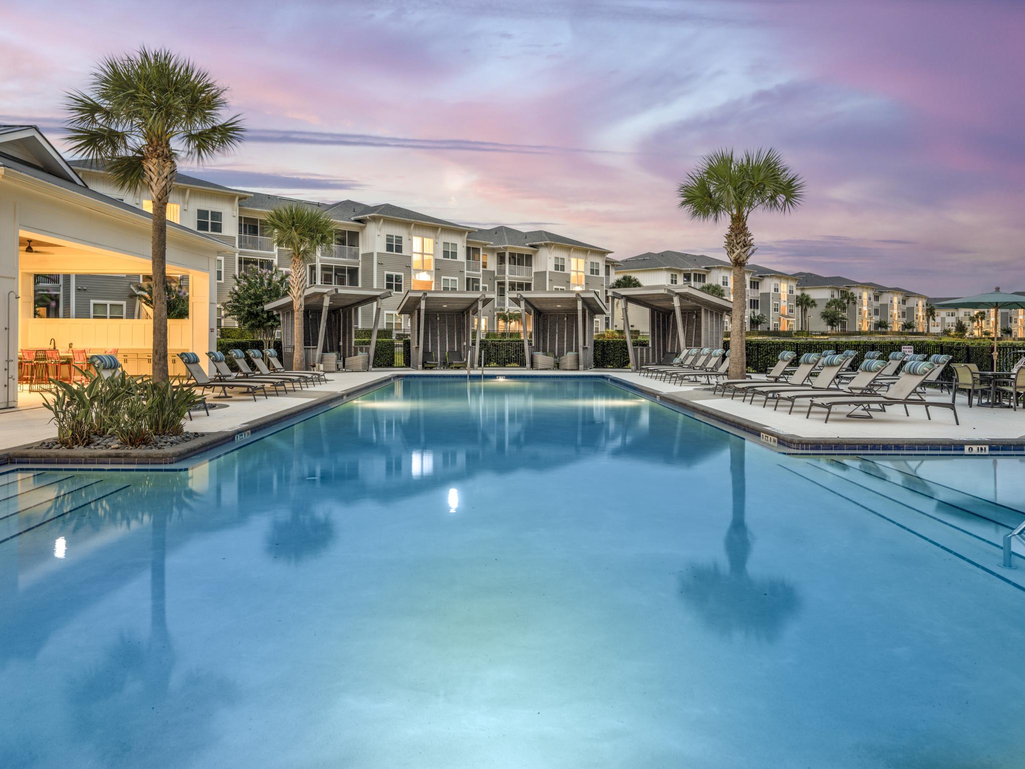 Sparkling, resort style swimming pool with twilight setting. Ample seating for residents to enjoy.