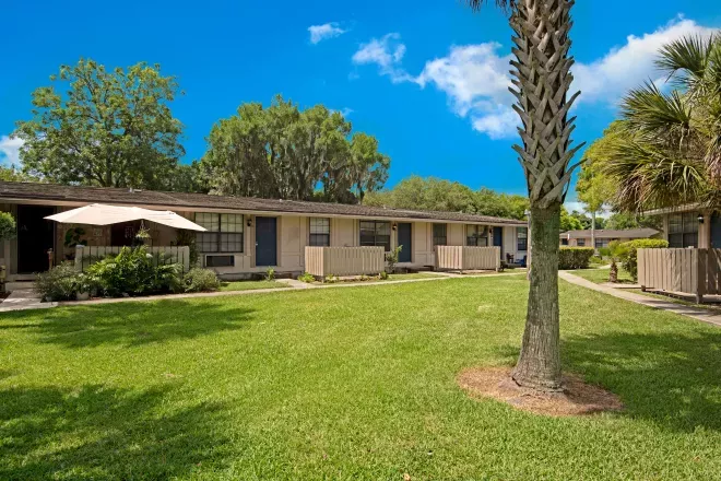 A row of well-maintained homes with a central lawn and shaded seating areas.
